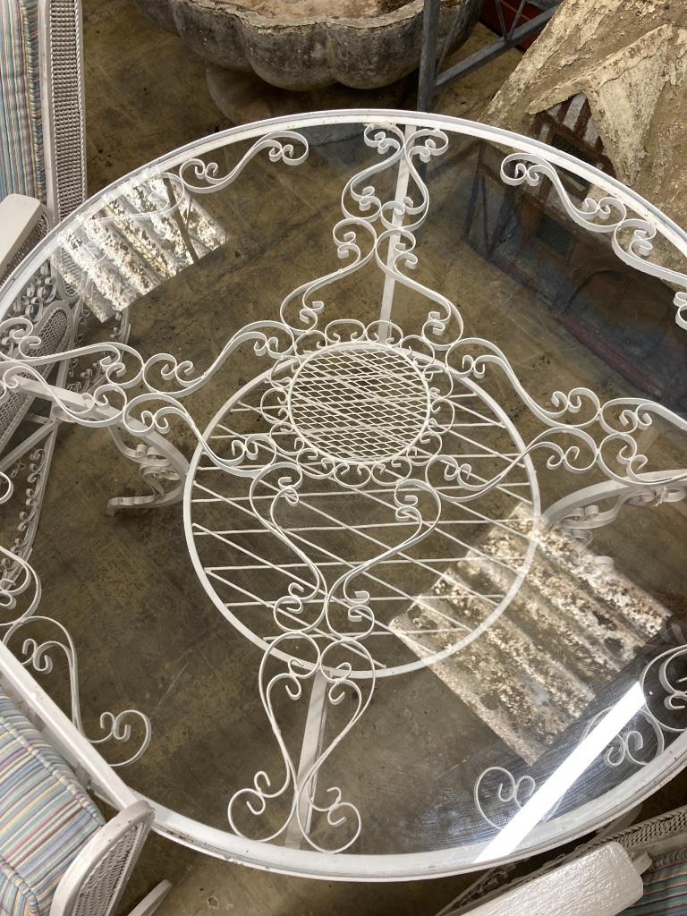 A wrought iron conservatory suite, comprising four armchairs and a large circular table, 100cm diameter, height 56cm, (reputedly made In Bahrain for the Persian Embassy circa 1960-65)